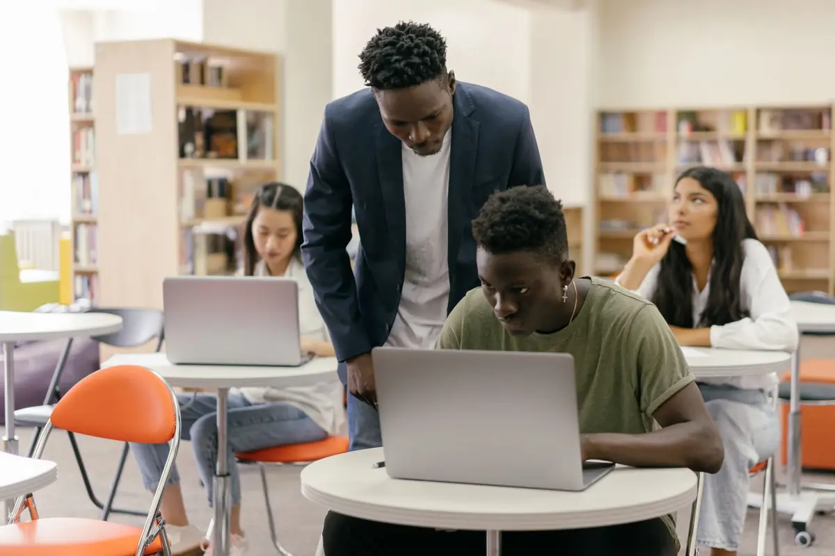 Tutor ayudando a un alumno con su laptop